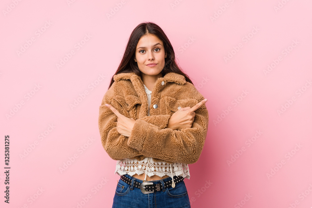Young cute woman points sideways, is trying to choose between two options. Young cute woman points sideways, is trying to choose between two options.