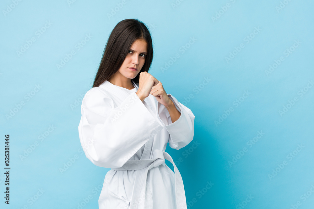 Young caucasian woman practicing karate isolated on a blue background Young caucasian woman practicing karate isolated on a blue background