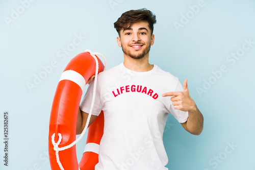 Young arabian lifeguard man isolated  person pointing by hand to a shirt copy space, proud and confident © Asier