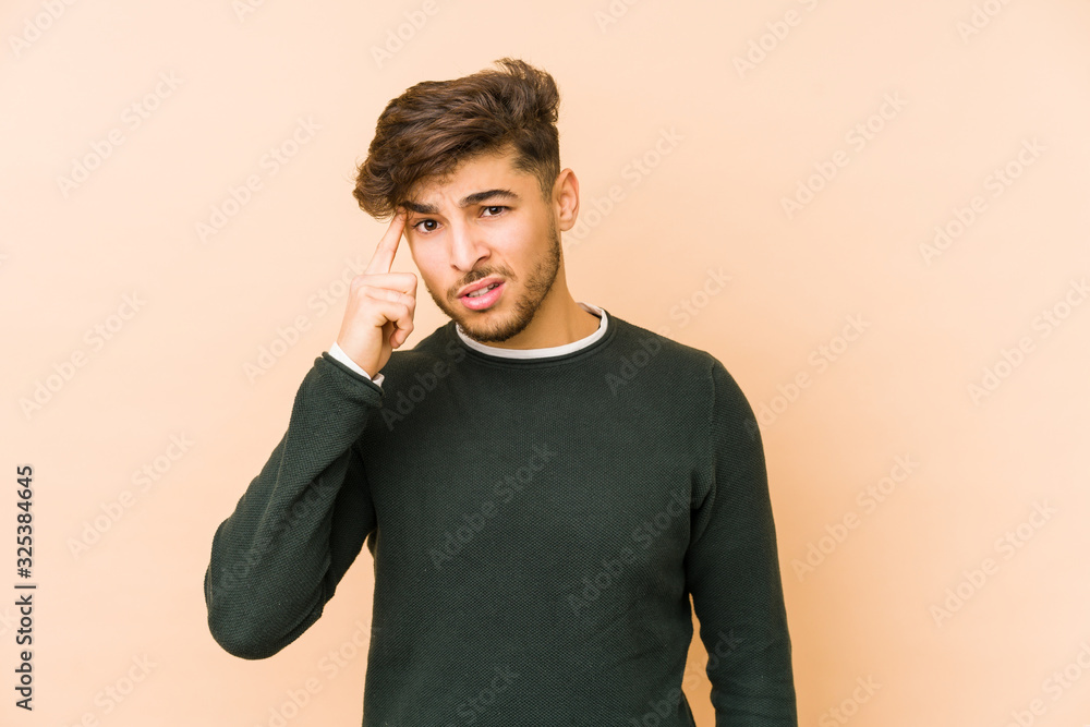 Young arabian man isolated on a beige background showing a disappointment gesture with forefinger. Young arabian man isolated on a beige background showing a disappointment gesture with forefinger.