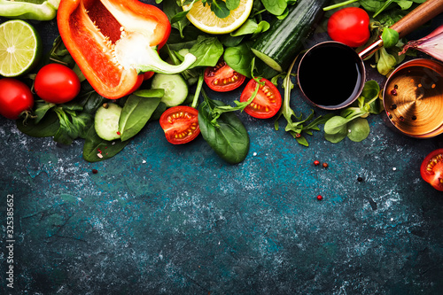 Fresh healthy food cooking or salad making ingredients on dark background with rustic wooden board. Diet or vegetarian food concept. Top view, copy space