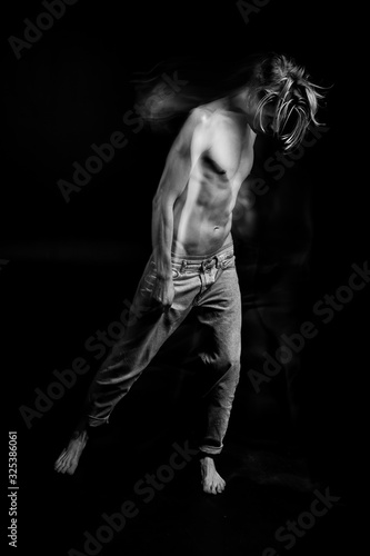 Dramatic emotional suffering man with a naked torso in jeans. stooped posture. depressed mood. Double personality back and white portrait. Long exposure creative moody creepy art works. feelings 