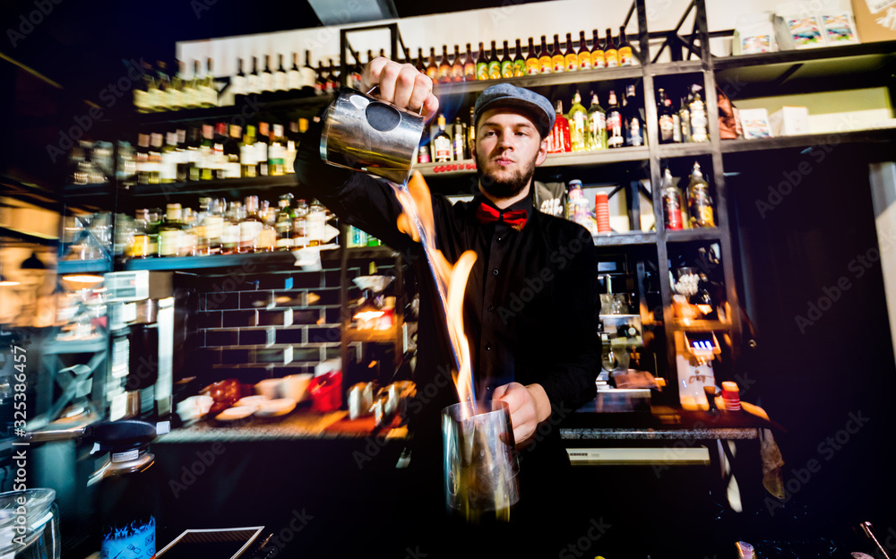 The bartender makes a cocktail with a fire show at the bar. 