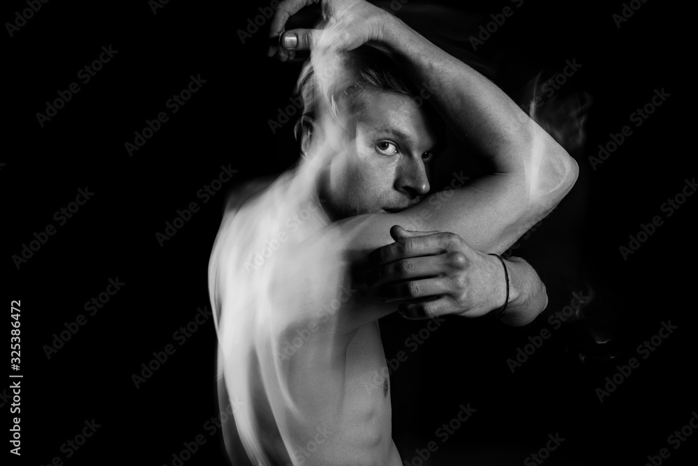 Fototapeta premium Handsome sports naked torso man looking to the camera. Creative emotional black and white portrait series with long exposure original technique. rebel suffering. looking with hope. arms raised