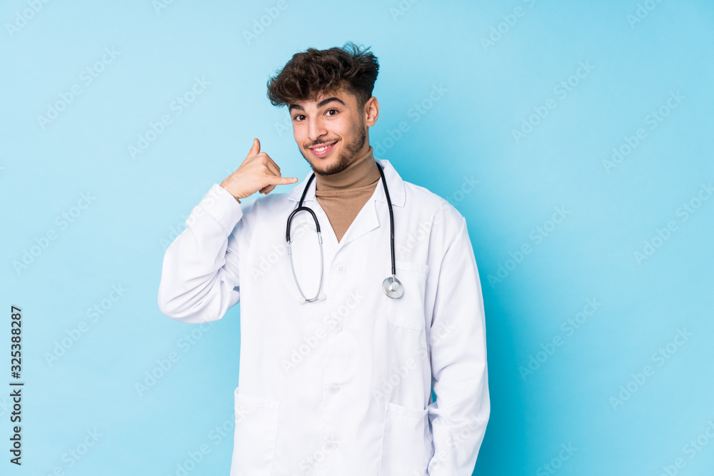Young arab doctor man idolated showing a mobile phone call gesture with fingers. Young arab doctor man idolated showing a mobile phone call gesture with fingers.