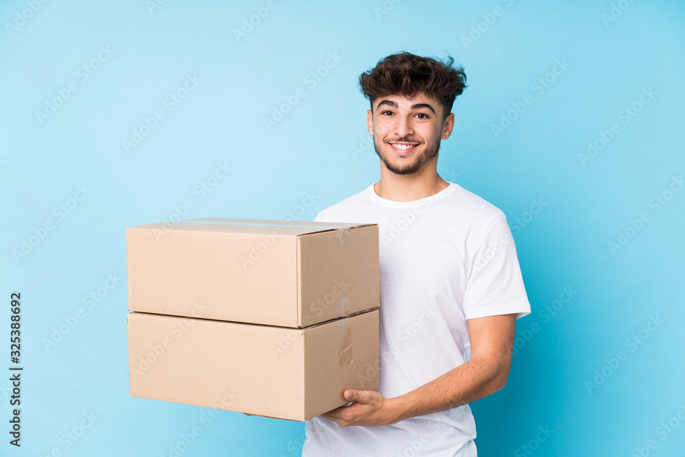 Young arab man holding boxes isolated laughing and having fun. Young arab man holding boxes isolated laughing and having fun.