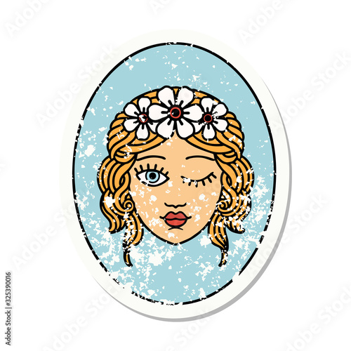 traditional distressed sticker tattoo of a maiden with crown of flowers winking