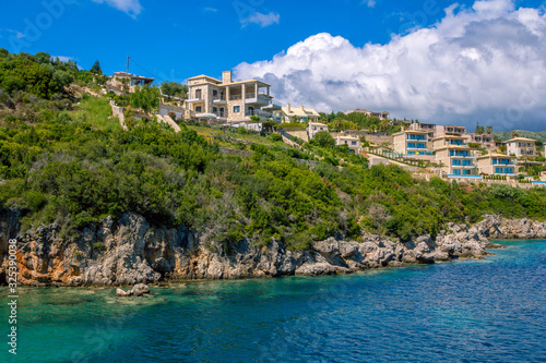 Fototapeta Naklejka Na Ścianę i Meble -  New villas and houses on the cliff over the sea with rocks in turquoise water. Summer landscape- green trees and blue sky. 