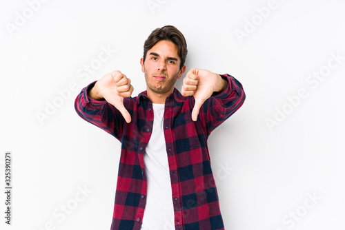 Young caucasian man posing in a pink background isolated showing thumb down and expressing dislike.