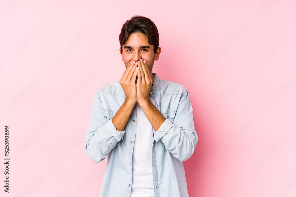 Young caucasian man posing in a pink background isolated laughing about something, covering mouth with hands. Young caucasian man posing in a pink background isolated laughing about something, covering mouth with hands.