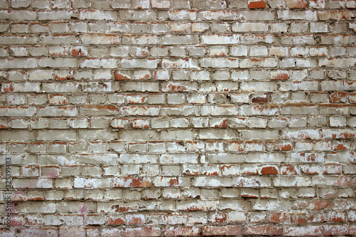  Old ragged, weathered red brick wall painted with white lime