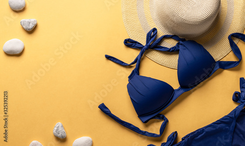 Travel vacation concept. Classic blue swimsuit and straw hat on a yellow background. horizontal image, place for text