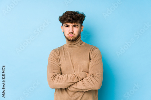 Young arabian man isolated blows cheeks, has tired expression. Facial expression concept.