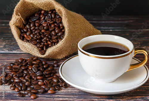  Black coffee in white cups and coffee beans on a black wooden floor.