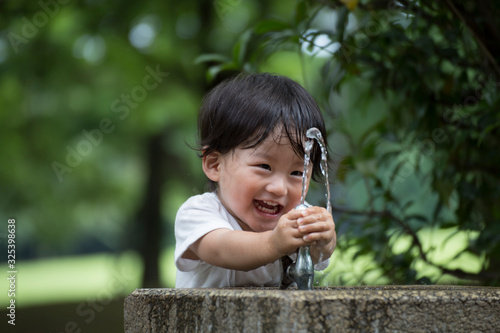 公園で水遊びをする無邪気で元気な男の子.
