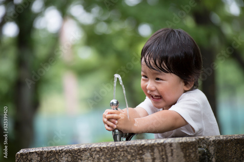 公園で水遊びをする無邪気で元気な男の子.