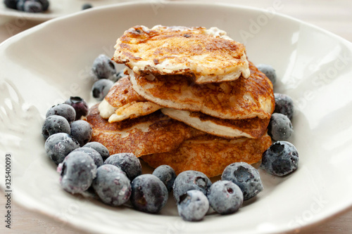 Low Carb Keto Diet Pancakes from almond coconut flour with blueberries, cream on white plate background close up view. Selective focus. Copy space. Ketogenic concept