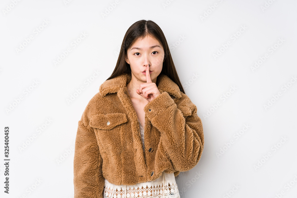 Young chinese woman posing in a white background isolated keeping a secret or asking for silence. Young chinese woman posing in a white background isolated keeping a secret or asking for silence.