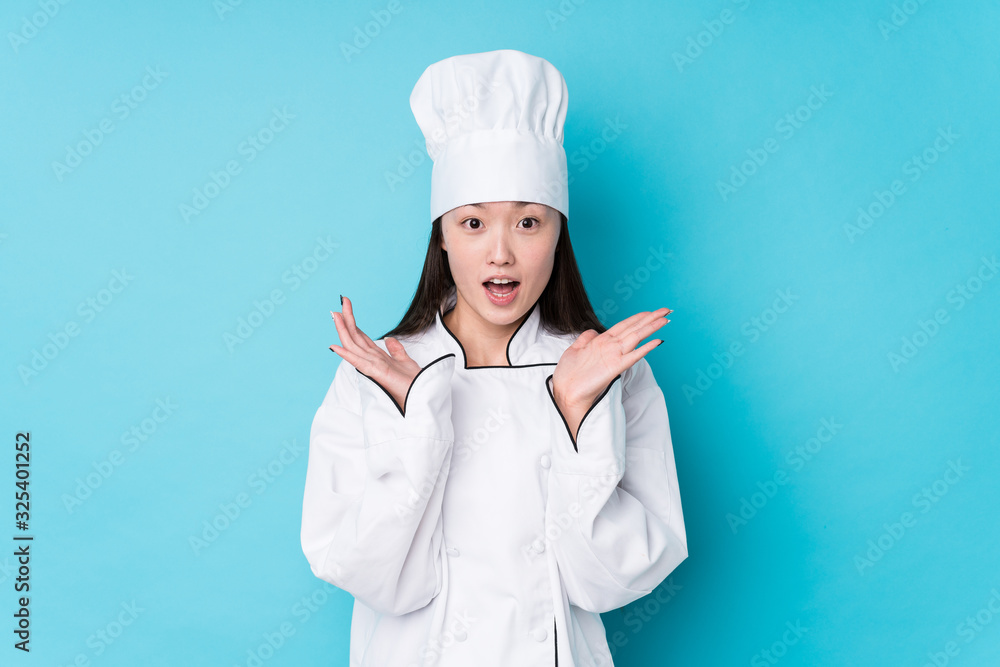 Young chinese chef woman isolated surprised and shocked. Young chinese chef woman isolated surprised and shocked.