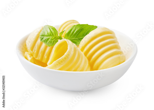 Butter curls or butter rolls in white bowl with fresh basil leaves isolated on white background.