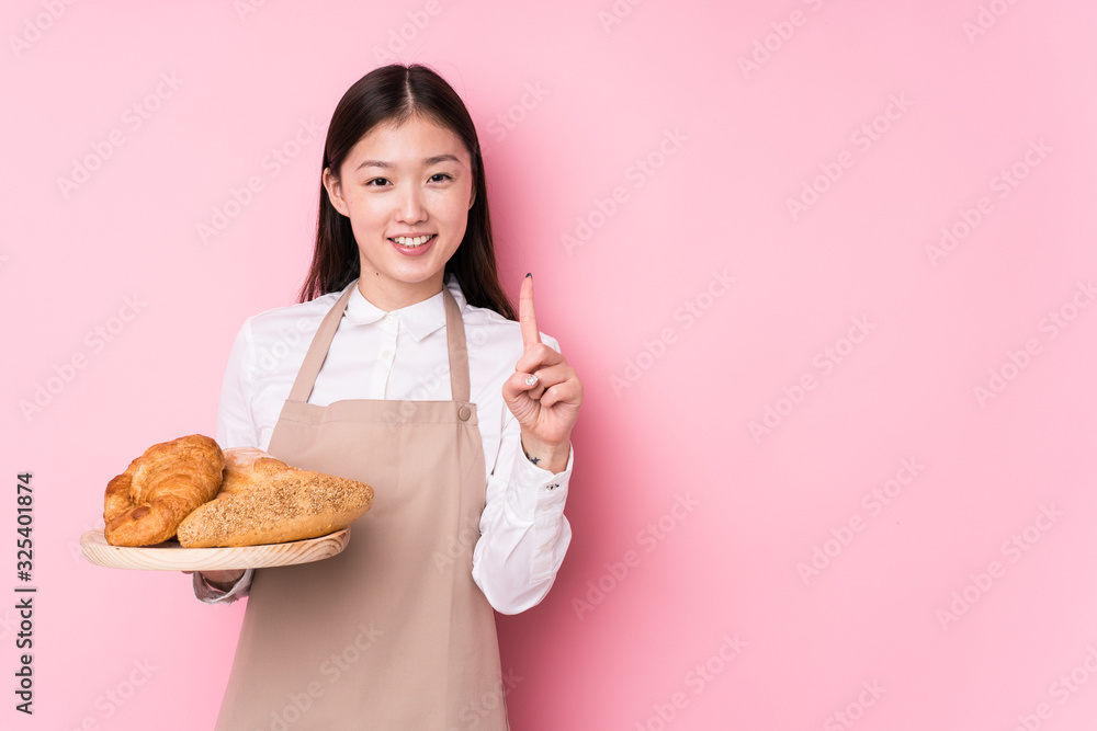 Young chinese baker woman isolated showing number one with finger. Young chinese baker woman isolated showing number one with finger.