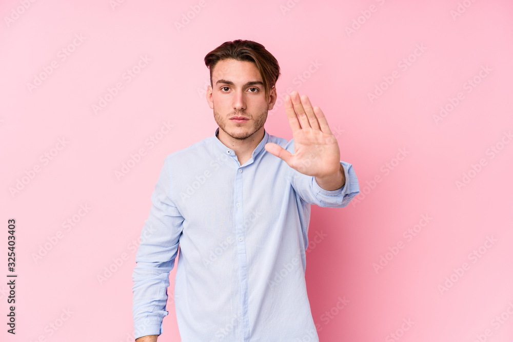 Young caucasian man posing in a pink background isolated standing with outstretched hand showing stop sign, preventing you. Young caucasian man posing in a pink background isolated standing with outstretched hand showing stop sign, preventing you.