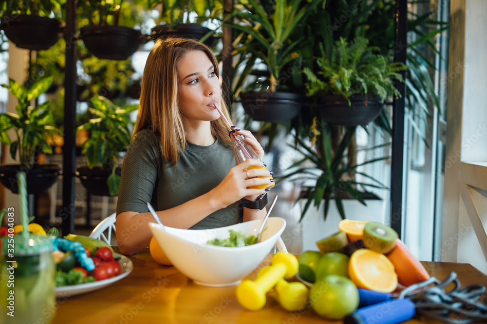 Positive fitness trainer hold fresh juice on hands for healthy care and body slim. Diet and healthy sport concept.Fresh food on the table Positive fitness trainer hold fresh juice on hands for healthy care and body slim. Diet and healthy sport concept.Fresh food on the table