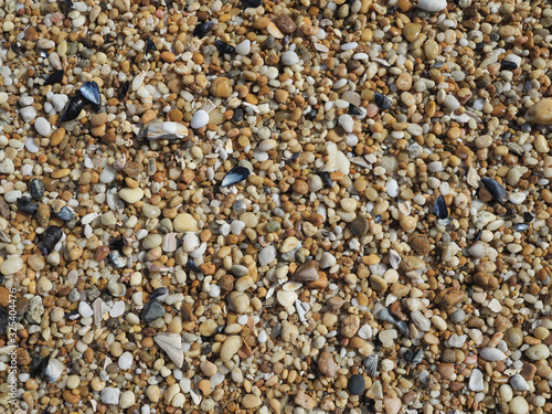 Small smooth pebbles and worn glass line the beach at low tide in the coastal community of Sea Girt New Jersey on the Atlantic Coast