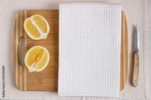 White kitchen waffle towel on wooden cutting board with fresh lemons. Product design