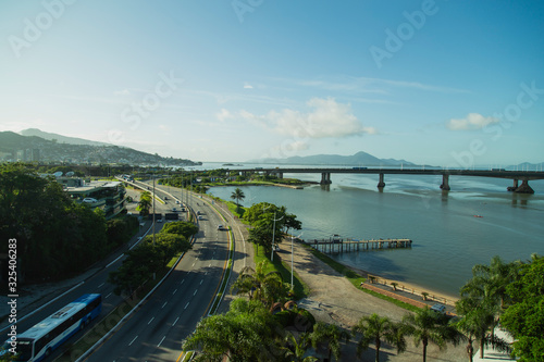 Panoramic view of Florianópolis city downtown. Beira-mar Avenue in the foreground, bridges and mountains in the background. Sunny day with clouds.