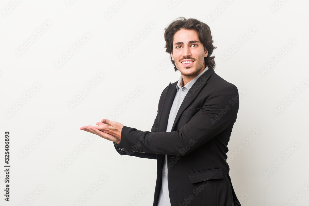 Young business man against a white background holding a copy space on a palm. Young business man against a white background holding a copy space on a palm.