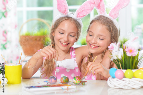 Cute twins wearing rabbit ears decorating Easter eggs