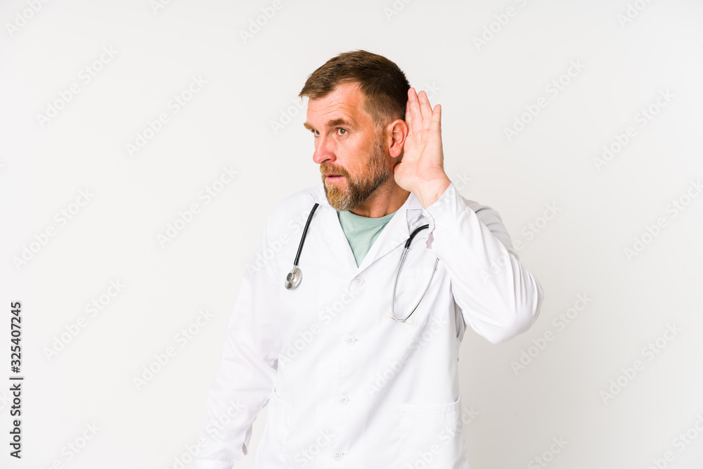 Senior doctor man isolated on white background trying to listening a gossip. Senior doctor man isolated on white background trying to listening a gossip.