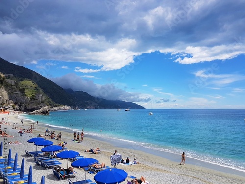 Italy, Cinque Terre, Monterosso Al Mare. Beautiful view of a beach along a coast line with turquoise sea and blue sky with clouds © Sasha Wallis