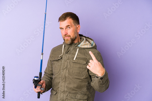 Senior fisherman isolated on purple background pointing with finger at you as if inviting come closer.