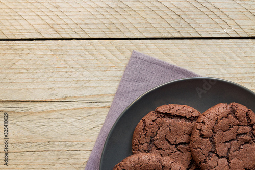 Top view of homemade chocoate cookies on black plate on wooden background. Home bakery photo