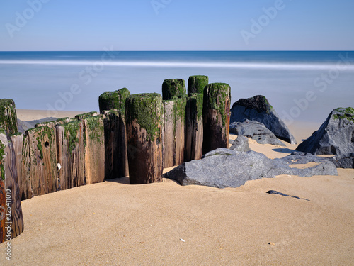 Old wood pilings worn and damaged by years of storms sit on a deserted winter beach in the New Jersey Coastal beach town of Sea Girt photo