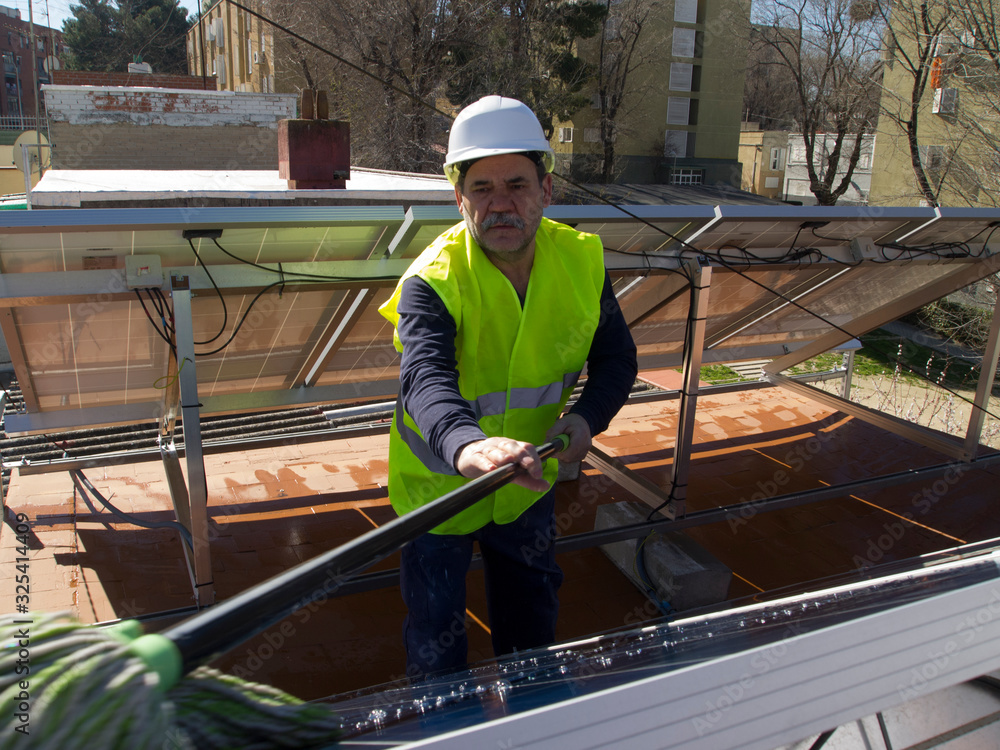 Caucasian seasoned technician cleaning the solar panels with a mop Caucasian seasoned technician cleaning the solar panels with a mop