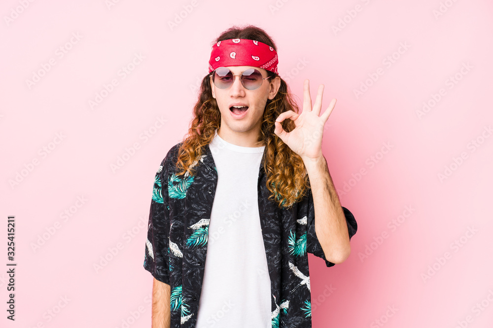 Young hippie caucasian man isolated winks an eye and holds an okay gesture with hand. Young hippie caucasian man isolated winks an eye and holds an okay gesture with hand.