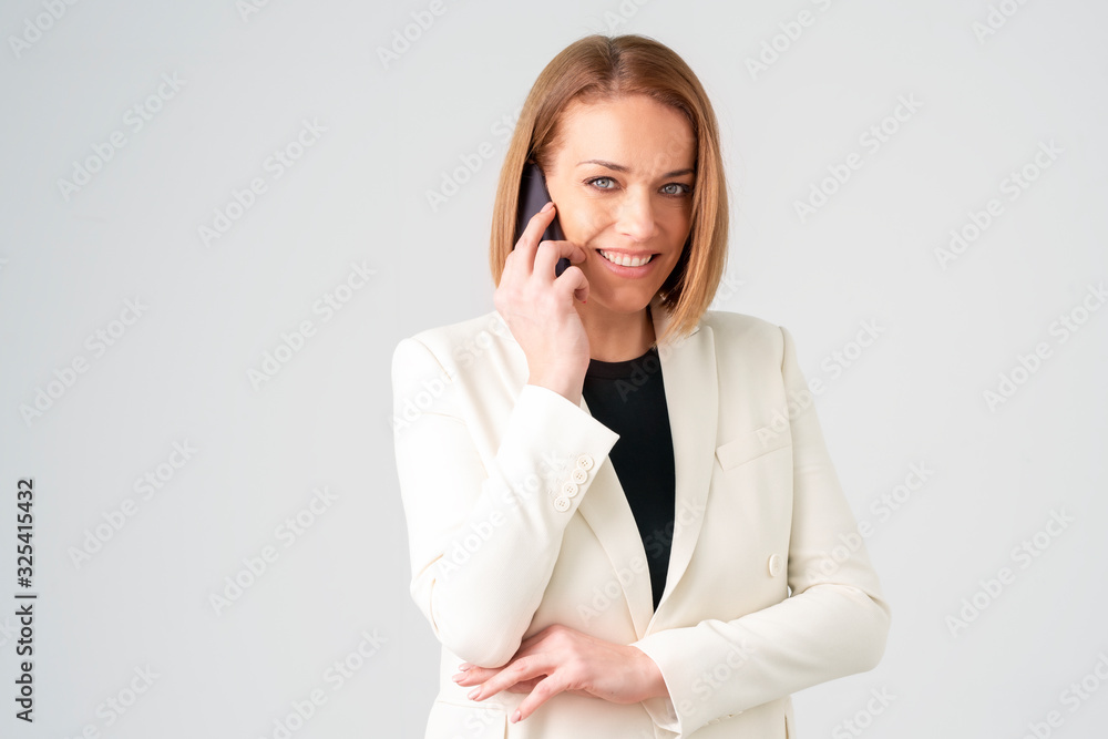 Close-up of middle aged businesswoman using her mobile phone while standing at isolated white background Close-up of middle aged businesswoman using her mobile phone while standing at isolated white background