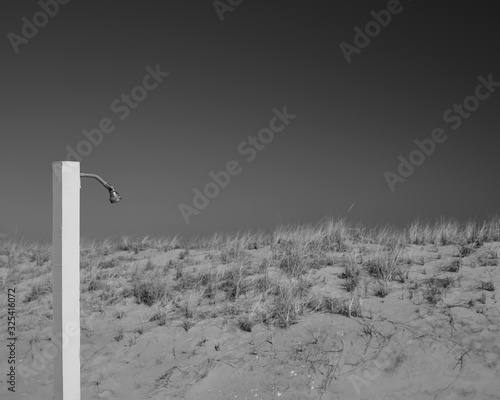 An abstract image of a beach goers shower head behind sand dunes on a deserted beach in winter in the beachtown of Sea Girt New Jersey photo