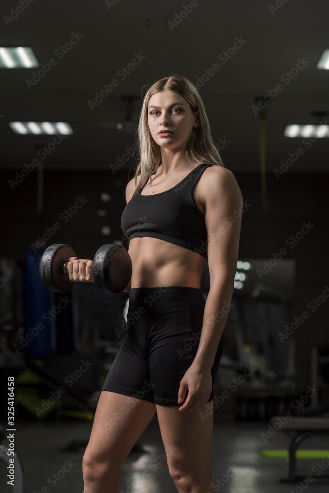 Portrait of a girl in a fitness gym with dumbbells. Portrait of a girl in a fitness gym with dumbbells.