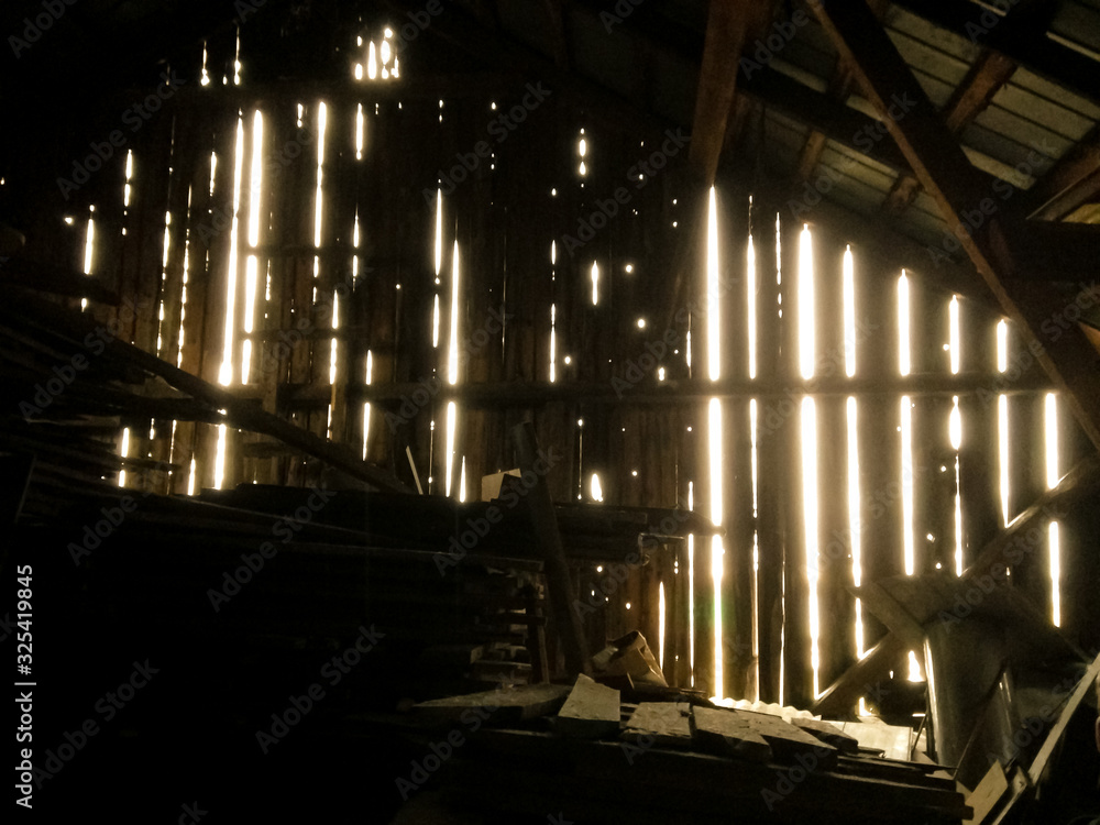 Interior of a Barn Slightly Illuminated by the Sun Entreing Holes Between the Wooden Planks in Quebec, Quebec / Canada