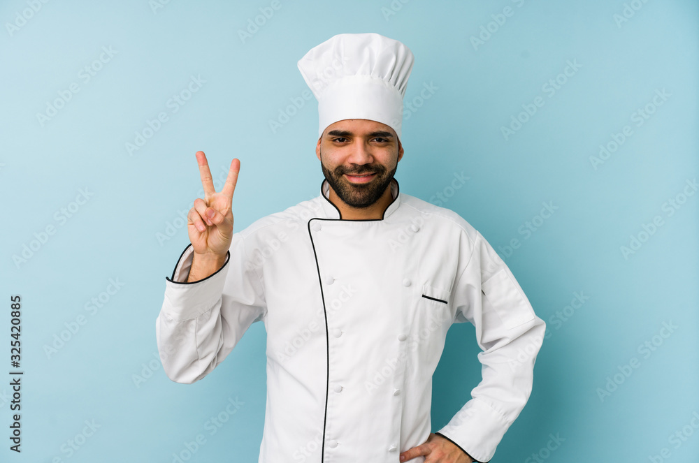 Young latin chef man isolated showing number two with fingers. Young latin chef man isolated showing number two with fingers.