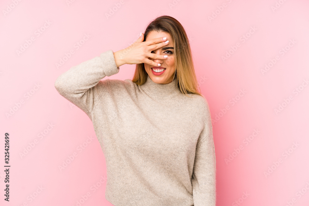 Middle age woman over isolated background blink at the camera through fingers, embarrassed covering face. Middle age woman over isolated background blink at the camera through fingers, embarrassed covering face.