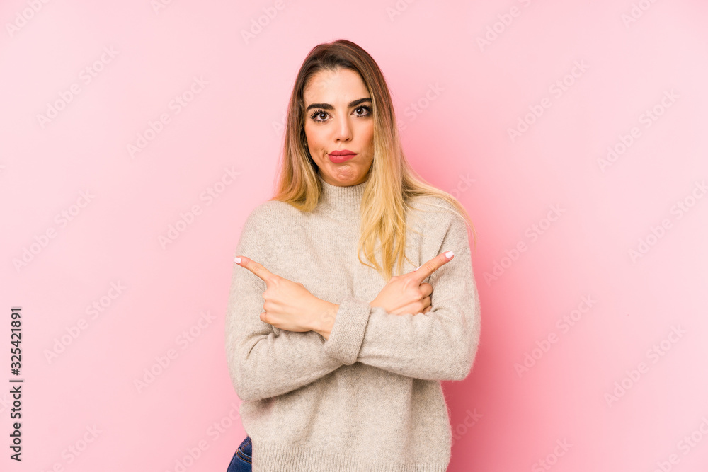 Middle age woman over isolated background points sideways, is trying to choose between two options. Middle age woman over isolated background points sideways, is trying to choose between two options.