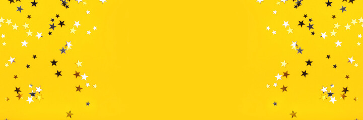 Golden and silver stars on yellow background. Flat lay, top view.