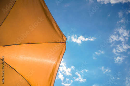 yellow umbrella on blue sky with clouds. Happy holiday vacation concept photo