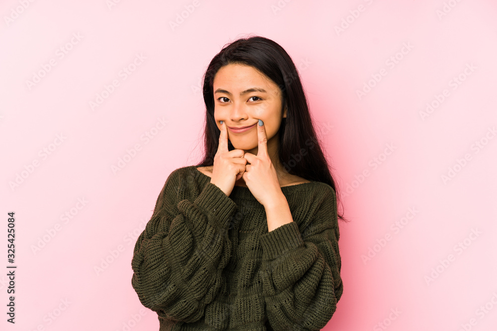 Young chinese woman isolated on a pink background doubting between two options. Young chinese woman isolated on a pink background doubting between two options.