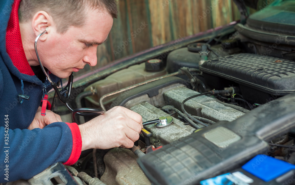 man with stethoscope checking car engine, auto service concept man with stethoscope checking car engine, auto service concept